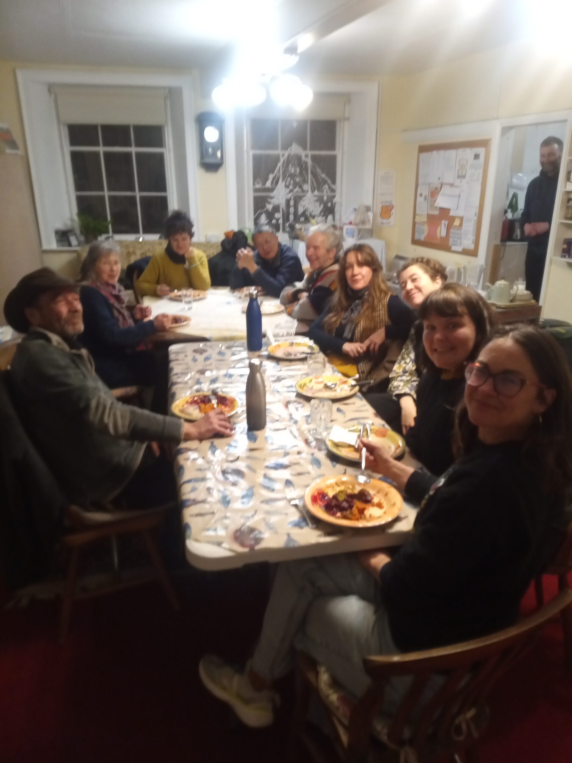People gathered around a table in the Reading Room at the Chapel in the Garden, sharing organic vegan curries during MMMM! Monday Movie, Meal & Mingling on 17 February 2025.